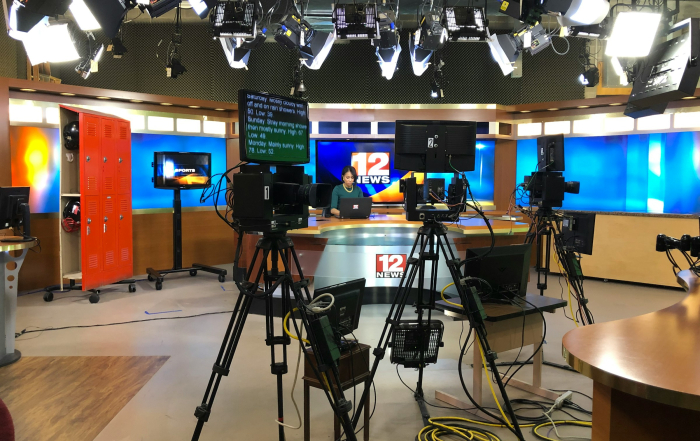 Presentadora de televisión en el plató de informativos con todo el material técnico.