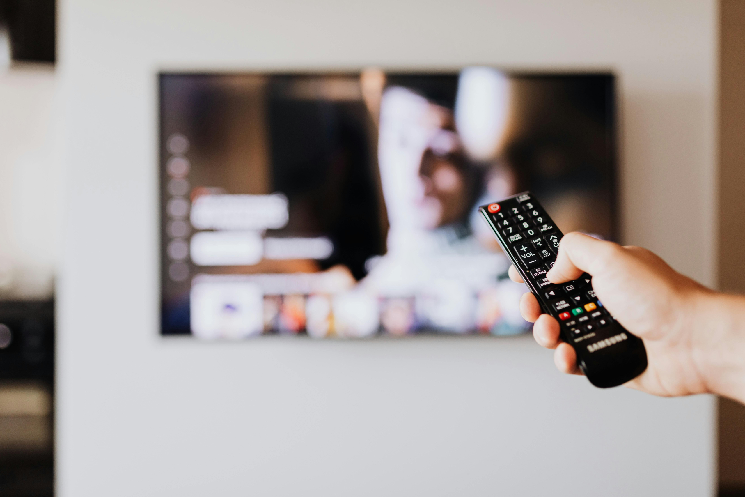 Mando de televisión Persona con un mando eligiendo los contenidos de la televisión