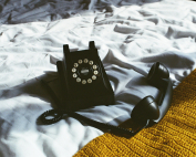 Teléfono fijo negro sobre unas sábanas