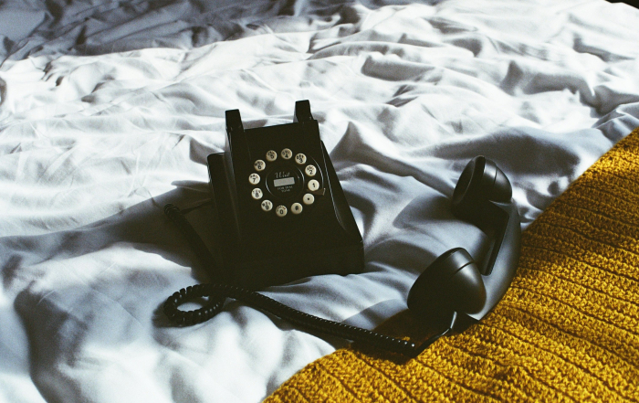 Teléfono fijo negro sobre unas sábanas