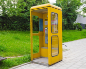 Cabina de teléfono amarilla en medio de la calle.