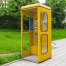 Cabina de teléfono amarilla en medio de la calle.