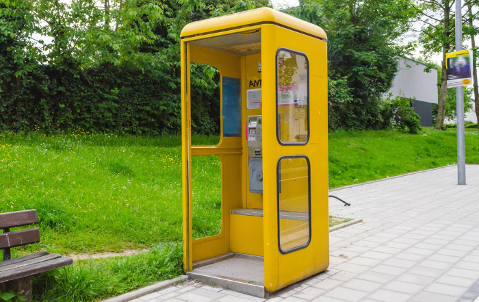 Cabina de teléfono amarilla en medio de la calle.