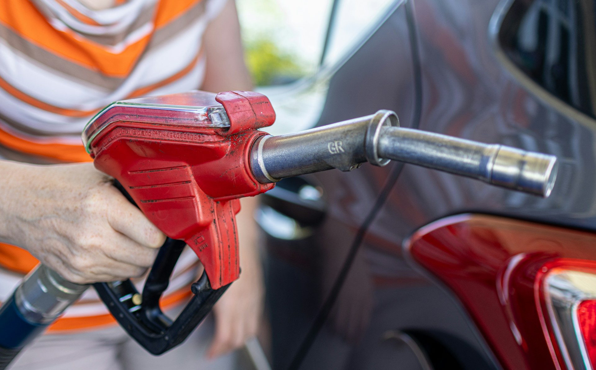 Hombre con una maguera de gasolina en la mano.
